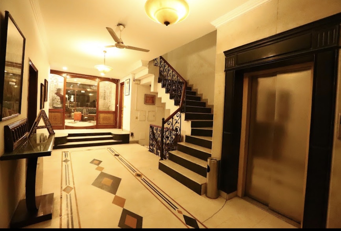 Hotel Ambica Palace — grand entrance lobby with staircase, chandelier and inlaid marble floor