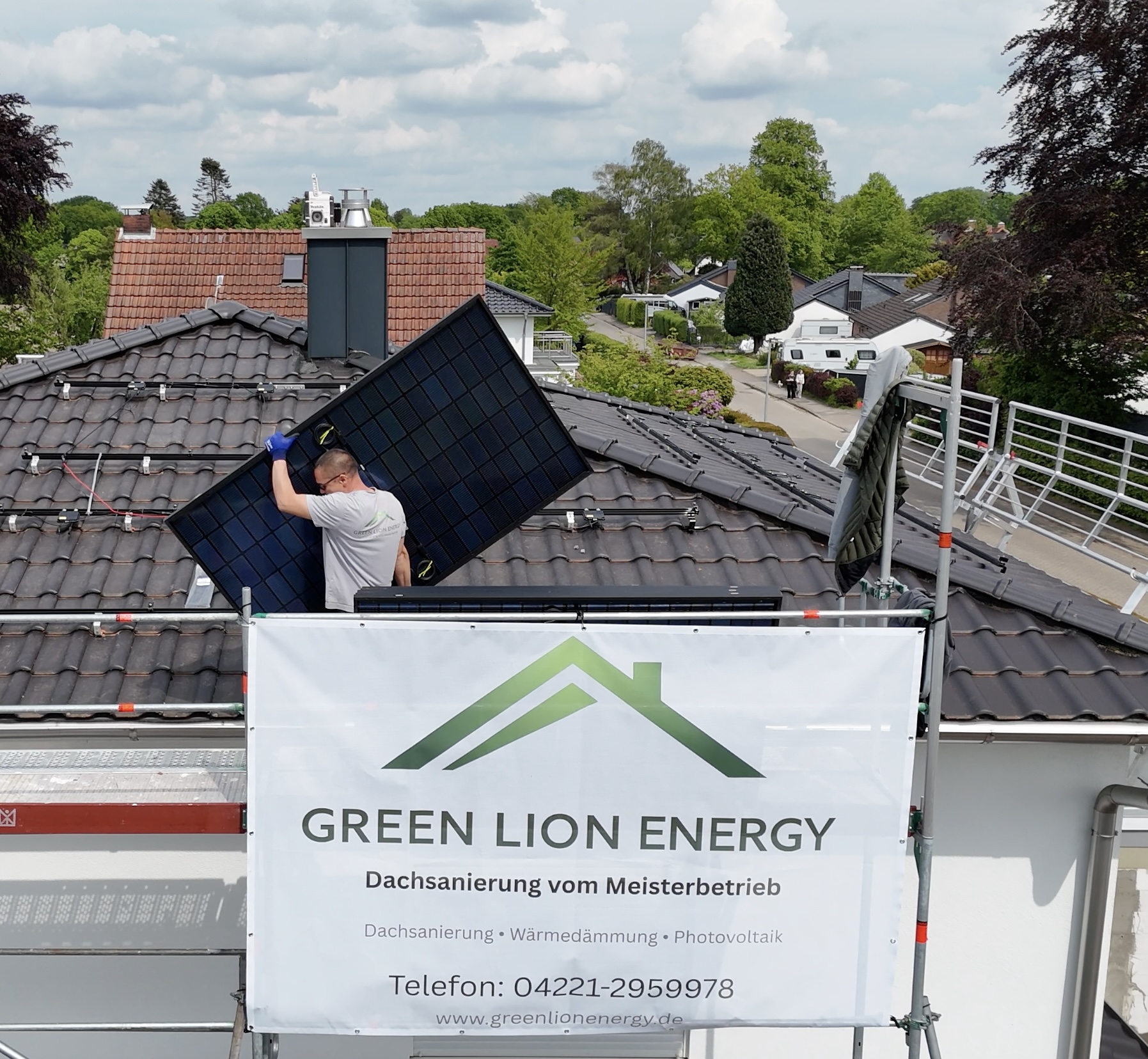Echte PV-Montage durch einen Green Lion Energy Mitarbeiter – Baustelle mit Green Lion Energy Banner am Gerüst