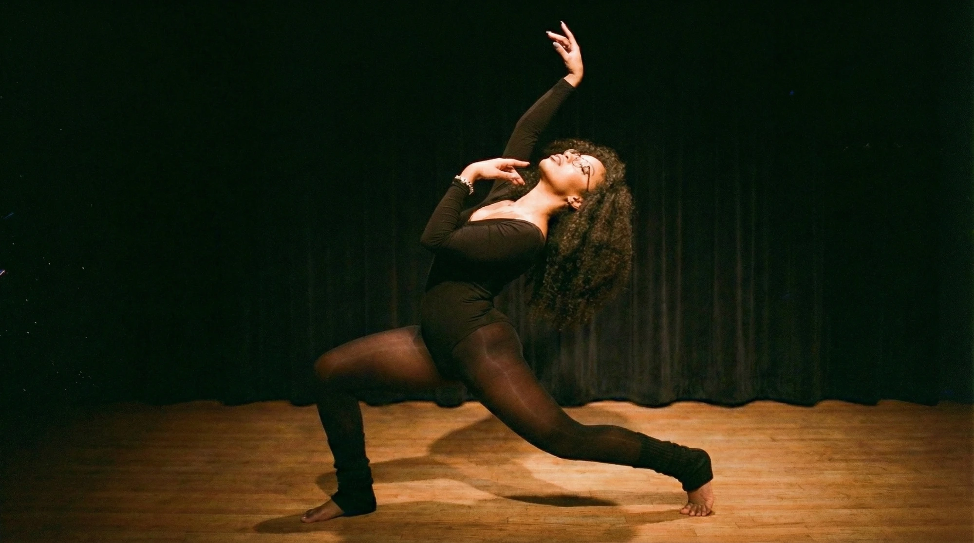 Dani in a backbend arc on a dark stage