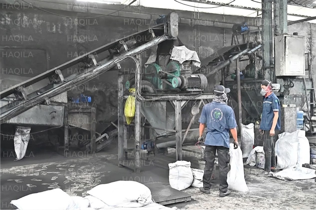 Coconut shell charcoal being processed on a crusher and conveyor line at a manufacturing partner's facility