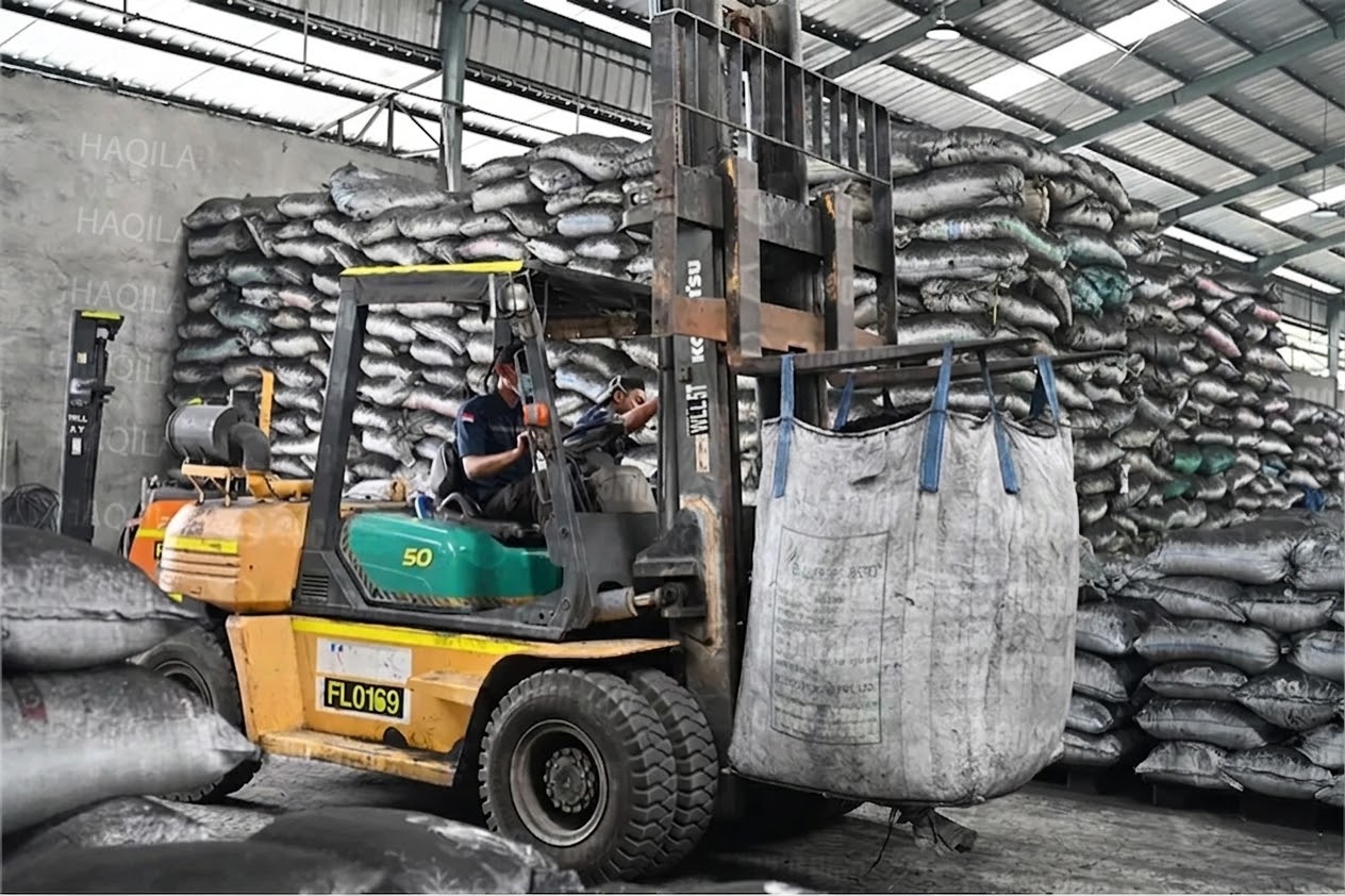 Forklift lifting a jumbo bag of coconut shell charcoal at a manufacturing partner's facility in Indonesia