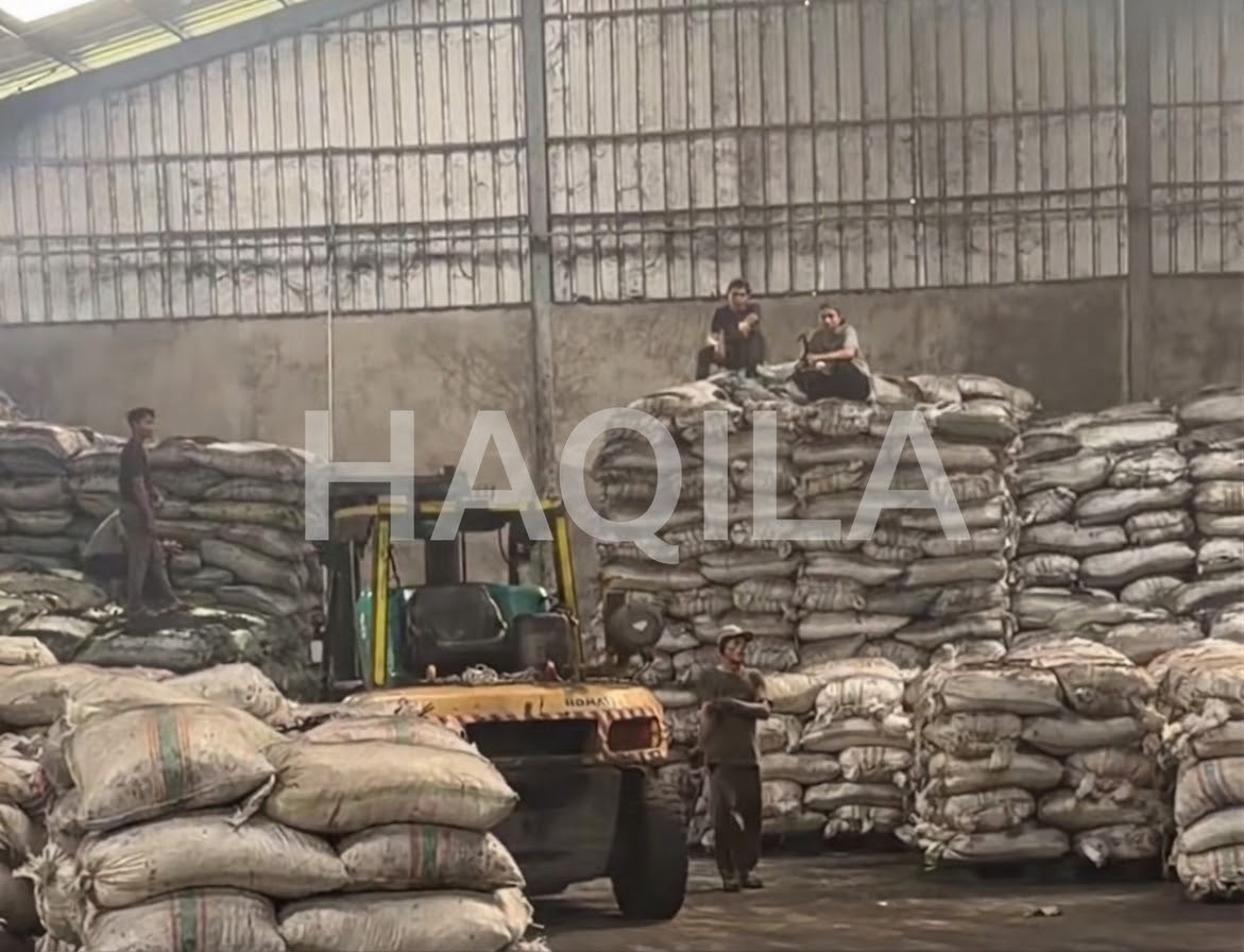 Forklift and stacked sacks of coconut shell charcoal in a manufacturing partner's warehouse