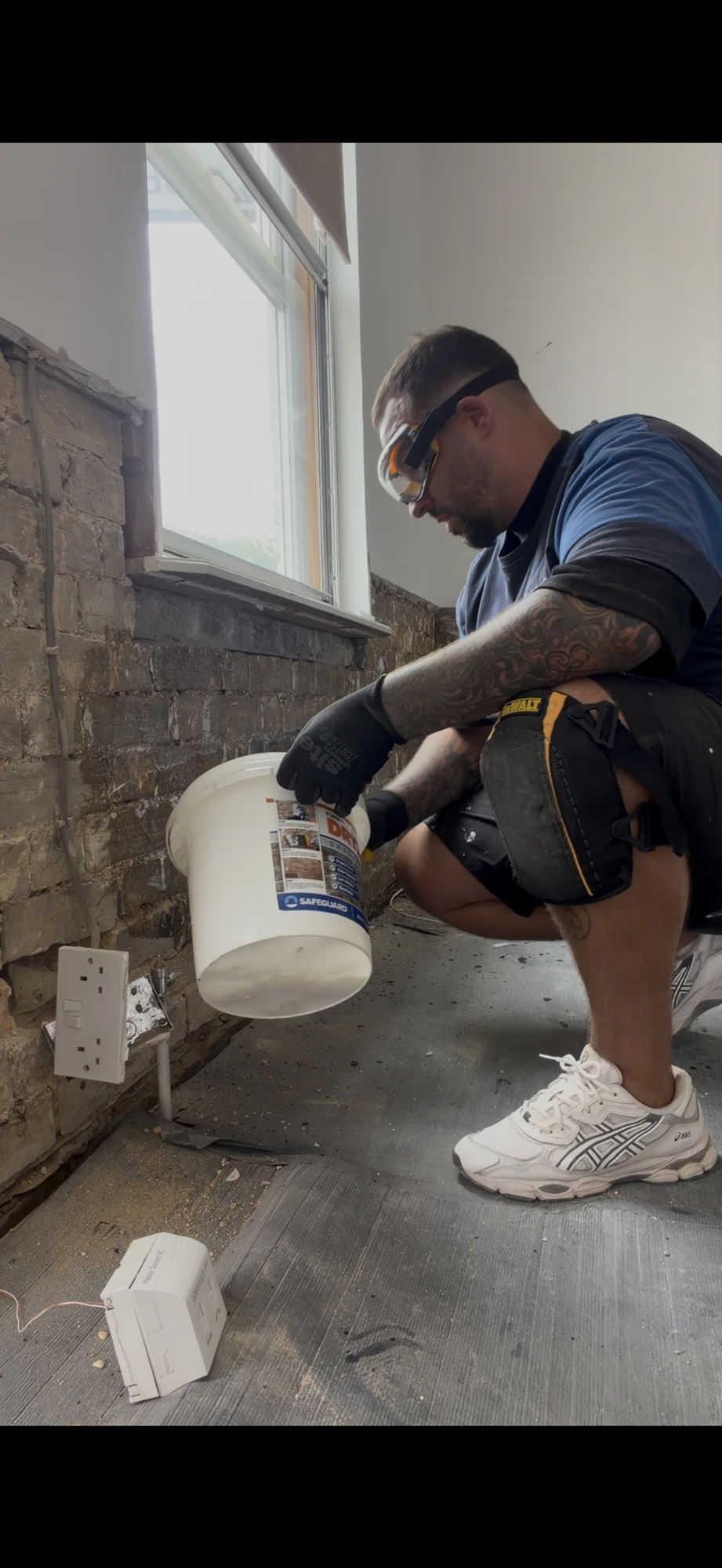A Procure Group technician applying a damp-proofing system to brickwork at floor level