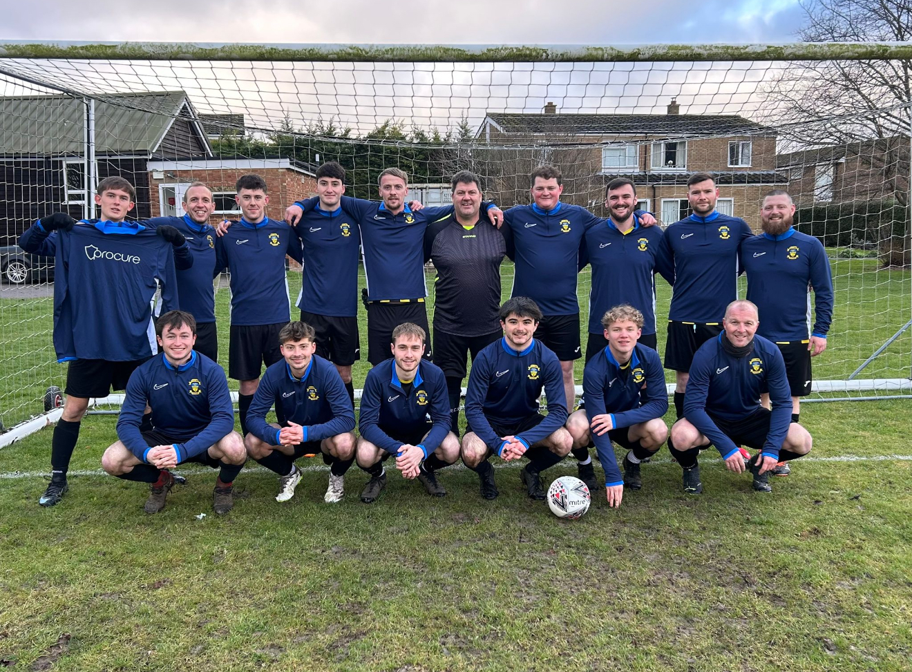 The local football team Procure Group sponsors, lined up in front of the goal holding a Procure-branded shirt