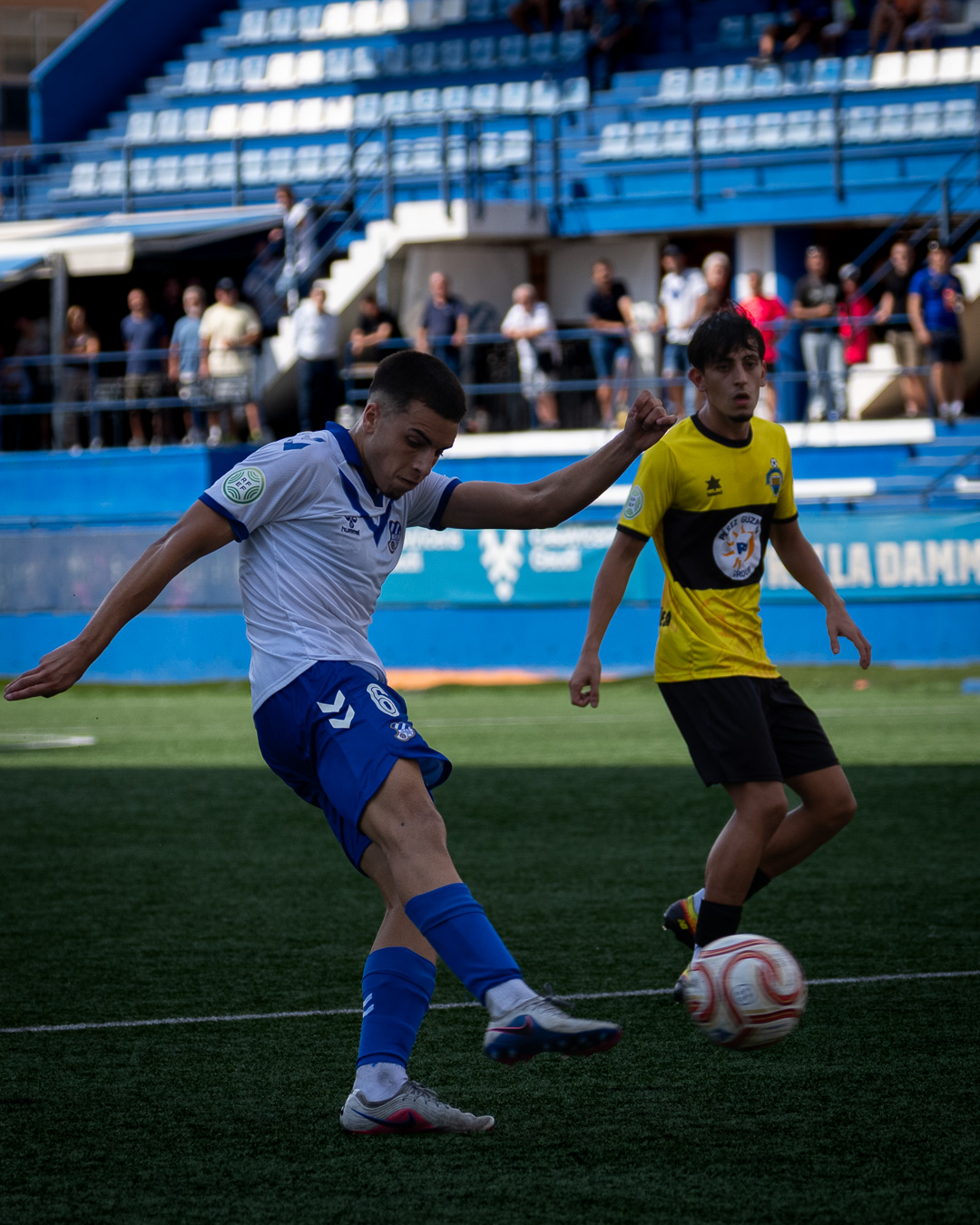 Player #6 striking the ball with a defender closing in