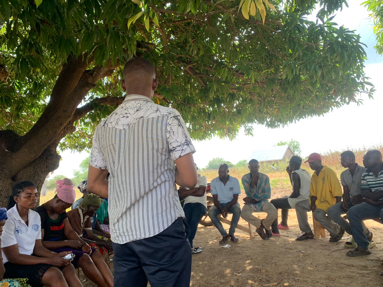 Yayra Glover field officer leading a farmer training session under a mango tree in rural Ghana